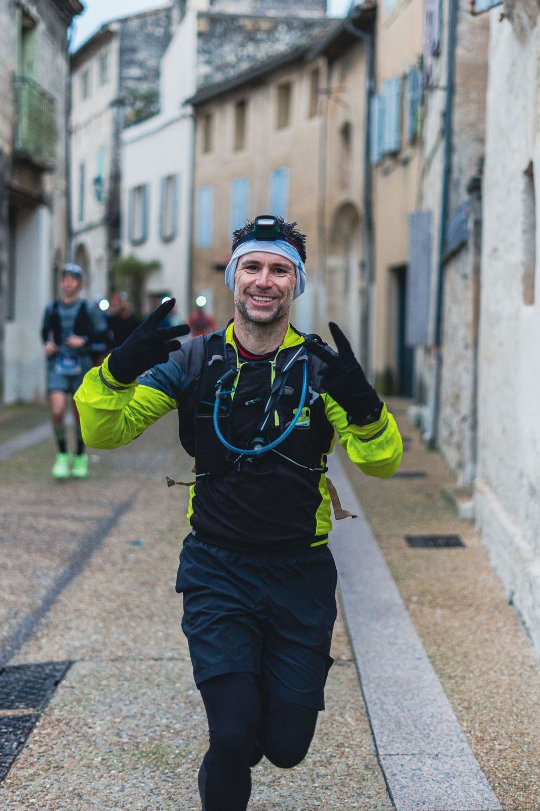 Coureur faisant le V dans une ruelle pavée