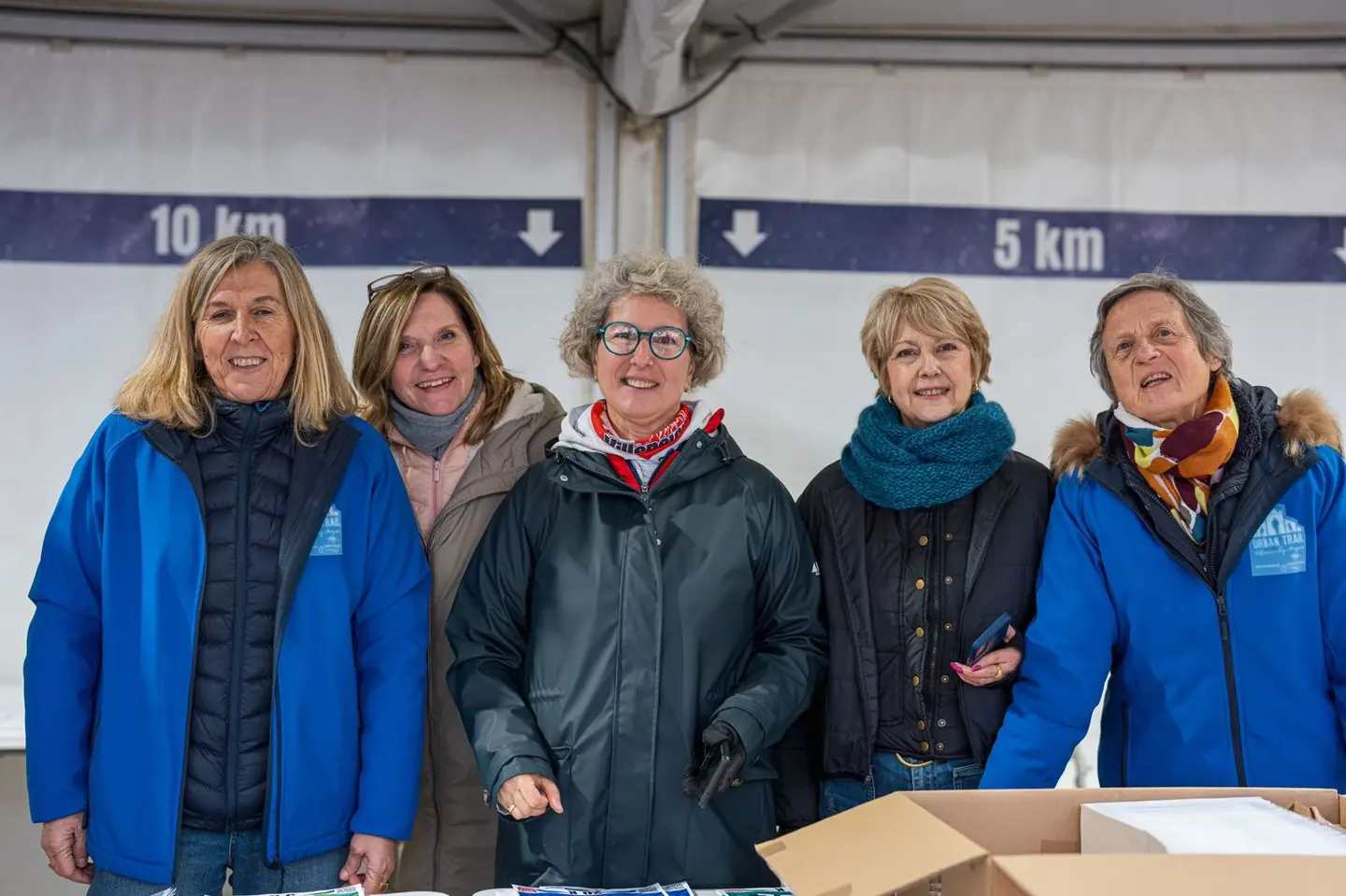 Cinq bénévoles souriantes au retrait des dossards