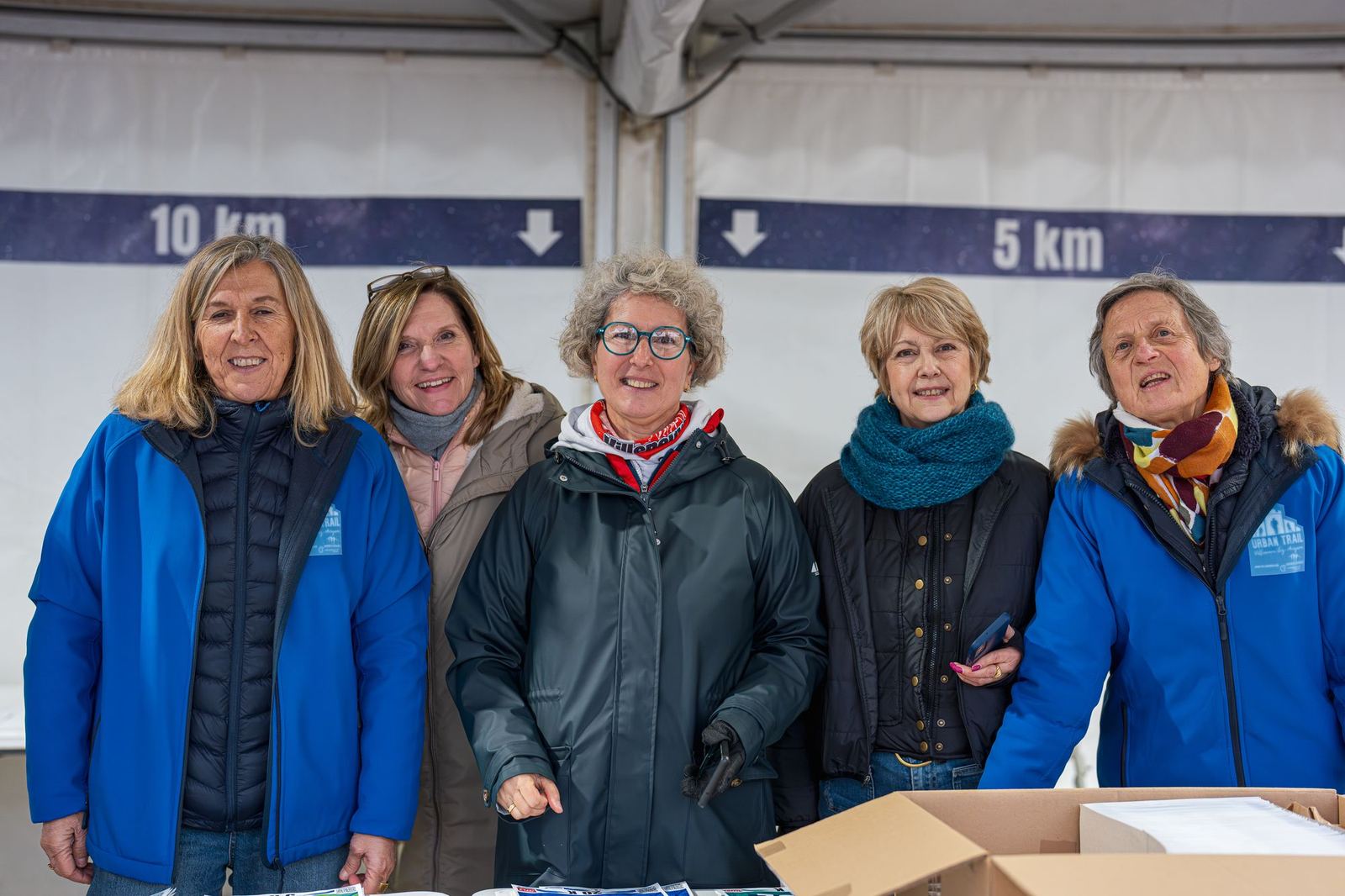 Cinq bénévoles souriantes au retrait des dossards